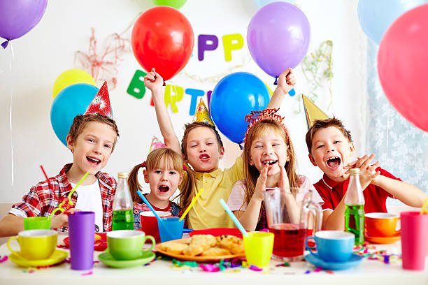 Kids celebrating birthday with balloons and cake.